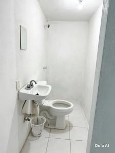 a white bathroom with a toilet and a sink at HM cuarteria cangrejos in Cabo San Lucas
