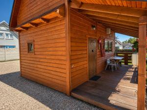 a large wooden cabin with a door and a patio at DOMKI NA FALI by Baltic Club in Sarbinowo