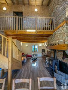 a living room with a staircase and a stone fireplace at Le castillon in Marignac