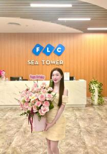 a woman holding a bouquet of flowers in an office at FLC Sea Tower Quy Nhơn - View Biển in Quy Nhon +96 photos