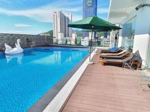 a swimming pool with an umbrella and swans on a building at FLC Sea Tower Quy Nhơn - View Biển in Quy Nhon