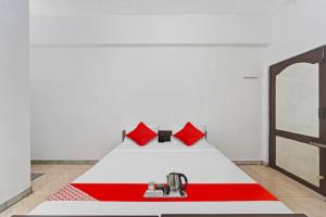 a bed with red pillows in a white room at Hotel O Grand Pallavaram in Chennai