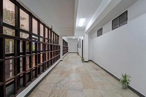 a hallway with white walls and windows and a tile floor at Hotel O Grand Pallavaram in Chennai