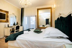a bedroom with a large white bed with a mirror at Pensiunea Cameea Busteni in Buşteni