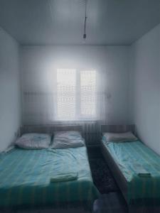 two twin beds in a room with two windows at House Ali in Klyuchi