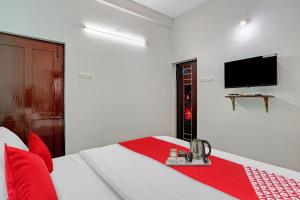 a bedroom with a bed with a tv on the wall at Hotel O Bevis in Trivandrum +18 photos