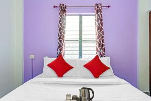 a bed with red and white pillows and a window at Hotel O Bevis in Trivandrum