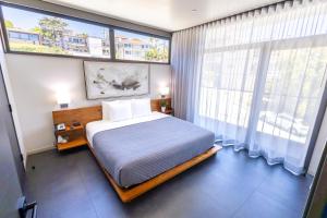 a bedroom with a bed and a large window at City24 Condo Hotel Little Italy Mission Hills in San Diego