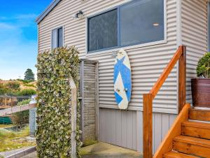 a house with a surfboard on the side of it at Six-Ten Shores in Dolphin Sands