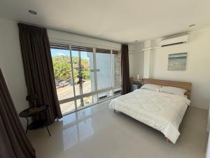 a bedroom with a bed and a large window at The CHU cafe / guesthouse in Nai Harn Beach