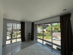 a bedroom with a bed and large windows at The CHU cafe / guesthouse in Nai Harn Beach