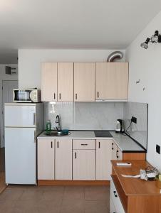 a kitchen with white cabinets and a white refrigerator at Sea Breeze Studio at Fort Noks Resort in Sunny Beach