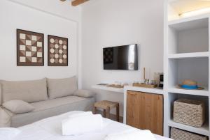 a living room with a couch and a tv at Aurum Suites Sifnos in Kamares