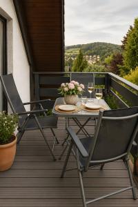 a table and two chairs on a deck with wine glasses at Ferienwohnung Am Wäldchen in Vöhl