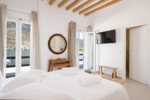 a white bedroom with two beds and a mirror at Aurum Suites Sifnos in Kamares