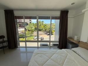 a bedroom with a bed and a large window at The CHU cafe / guesthouse in Nai Harn Beach