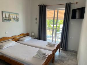 two twin beds in a room with a balcony at Golden Beach Sea View in Nea Mesangala