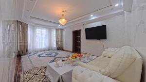 a living room with a white couch and a tv at ESAL House in Karakol