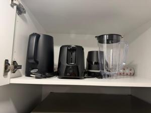 a kitchen shelf with a blender and appliances on it at Modern Rangeview Stay Near YMCA & Cineplex Cinema in Calgary