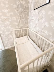 a white crib in a room with wallpaper at Lägenhet med trädgård på Österlen, nära hav & golf in Gärsnäs