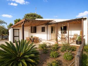 a small white house with a table and chairs at Casa del Carrubo con Piscina, relax in campagna vicino al mare in Santa Croce Camerina