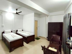 a room with two beds and a chair in it at Hotel Zirora in Ziro