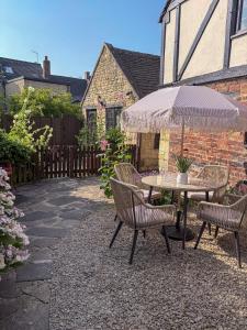 a patio with a table and chairs and an umbrella at Castle Cottage Winchcombe in Winchcombe