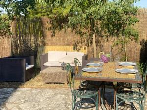 a table with chairs and a couch in a yard at Les OLIVETTES CLIMATISÉES d'UZES à Garrigues Sainte Eulalie in Garrigues-et-Sainte-Eulalie