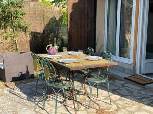 a wooden table with four chairs on a patio at Les OLIVETTES CLIMATISÉES d'UZES à Garrigues Sainte Eulalie in Garrigues-et-Sainte-Eulalie +8 photos