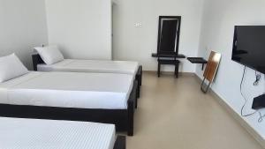 a room with two beds and a flat screen tv at RoaBaa Guesthouse in Batticaloa
