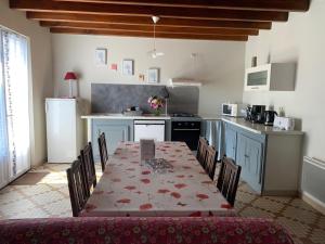 a kitchen with a table and chairs and a kitchen with a table and a table at Au lic in Montsoué