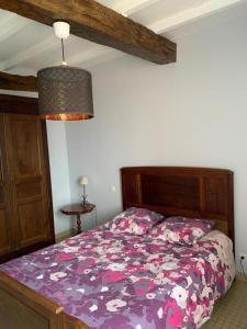 a bedroom with a bed with a purple comforter at Au lic in Montsoué +5 photos