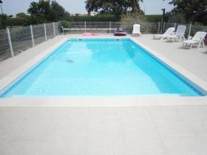 a large swimming pool with blue water in a yard at Au lic in Montsoué