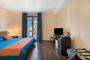 a bedroom with a bed and a tv and a window at Foresteria BB Sul Lago in Porlezza