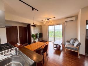 a kitchen and living room with a wooden table at CondoYumangi in Onna