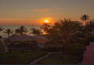 a sunset over a house with palm trees and the ocean at Villa Beside Swiming Pool With Garden View in Ban Map Khangkhao