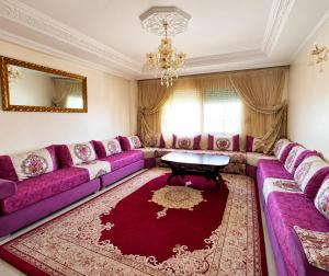 a living room with purple couches and a red rug at Stylish and valm appartement in Kenitra