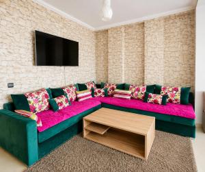 a living room with a pink couch and a tv at Stylish and valm appartement in Kenitra
