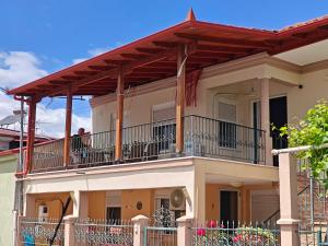 a house with a balcony with a man sitting on it at Harys Home in Korinos