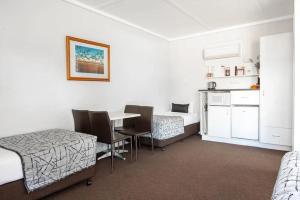 a room with two beds and a table and a kitchen at Nicholas Royal Motel - Hay CBD in Hay