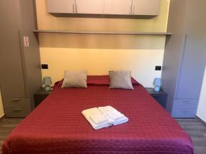 a bedroom with a red bed with two towels on it at Casa del Cerbiatto, Lake Como a 5 chilometri da Argegno in Castiglione dʼIntelvi