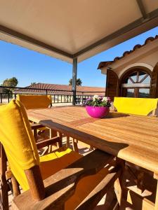 a wooden table with yellow chairs and a bowl of flowers at Tproject in Preveza