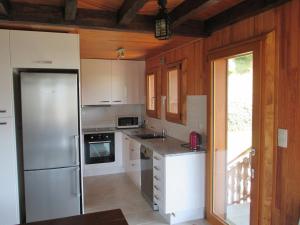 a kitchen with white cabinets and a stainless steel refrigerator at Comfortable Chalet with spectacular mountain views in Verchaix