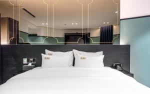 a bedroom with a large white bed with a large mirror at 호텔 어게인 in Cheongju