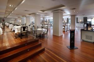 a dining room with white tables and chairs and wood floors at Parador de Vielha Spa & Wellness in Vielha