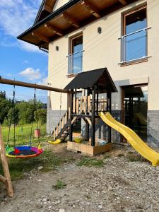 a playground in front of a house with a slide at Tatra Widok in Bukowina Tatrzańska