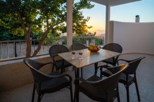 a table with wine glasses and chairs on a patio at Zia Village Miro in Lagoúdi Zía