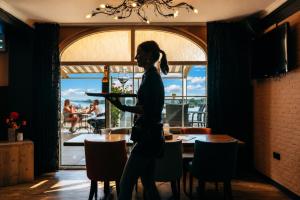 a woman walking through a restaurant with a table and chairs at Hotel Hoogeerd by Flow Niftrik - Nijmegen in Niftrik