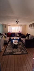 a living room with couches and a rug at Nchaman Nest in Loiyangalani 