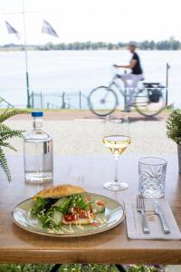 a plate of food on a table with a glass of wine at Hotel Hoogeerd by Flow Niftrik - Nijmegen in Niftrik